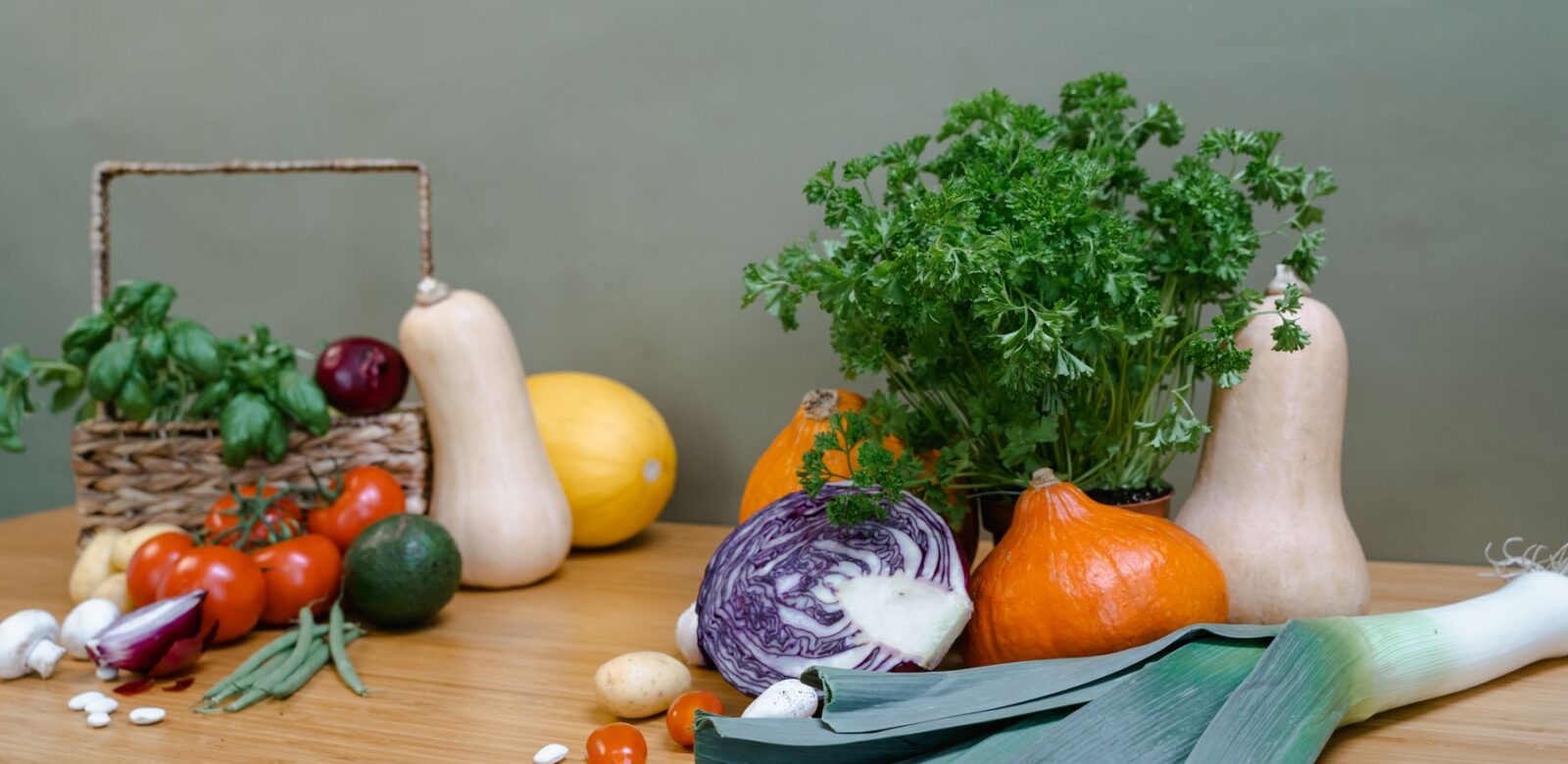 Kürbis, Rotkohl, Zwiebeln, Lauch und Kräuter auf einem Holztisch
